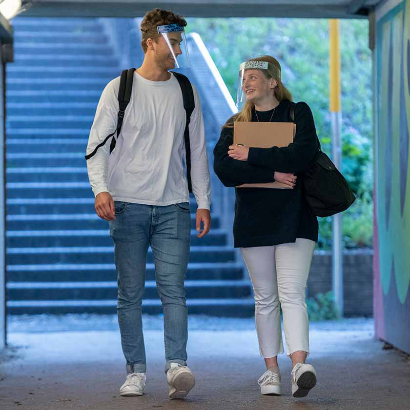 Male and female students chatting whilst wearing Medworx face shields with customisable stickers to match outfits. 
