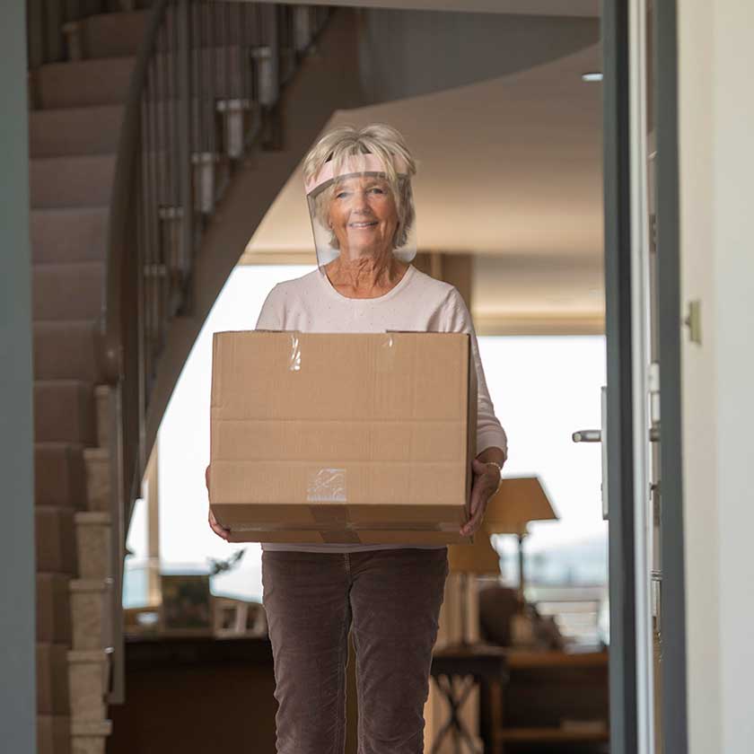 women collecting a delivery to her home wearing the Medworx face shield with a baby pink sticker to match her pink jumper. 